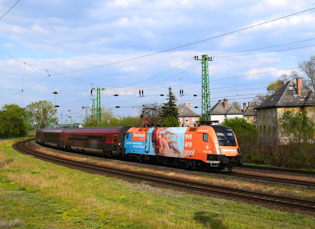 Die Werbelok  Steinbach  1116 229 mit dem Zug RJX 68 von Budapest nach München kurz nach Komárom.
30.04.2022.
