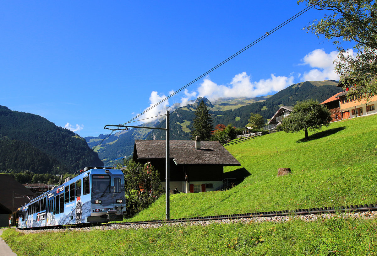 Die Wölkchen über den Bergen verkünden das Wegziehen einer Regenfront. Derweil erklimmen die Panoramatriebzüge 142 (mit Tissot-Reklame) und 148 die Steigung zum Bahnhof Grindelwald. 3.September 2019 