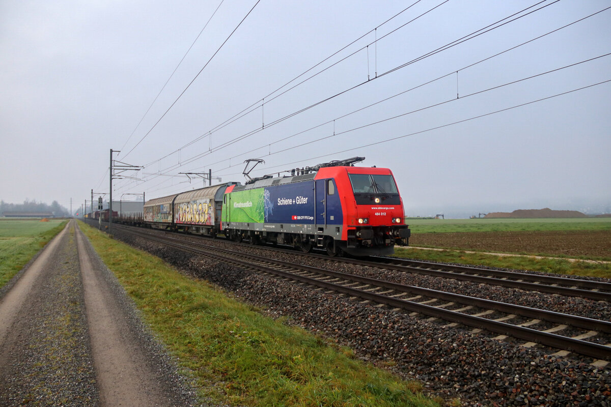 Die ziemlich frisch lackierte Re 484 012 fährt mit einem Güterzug durch Rafz Richtung Singen. 6.12.2022