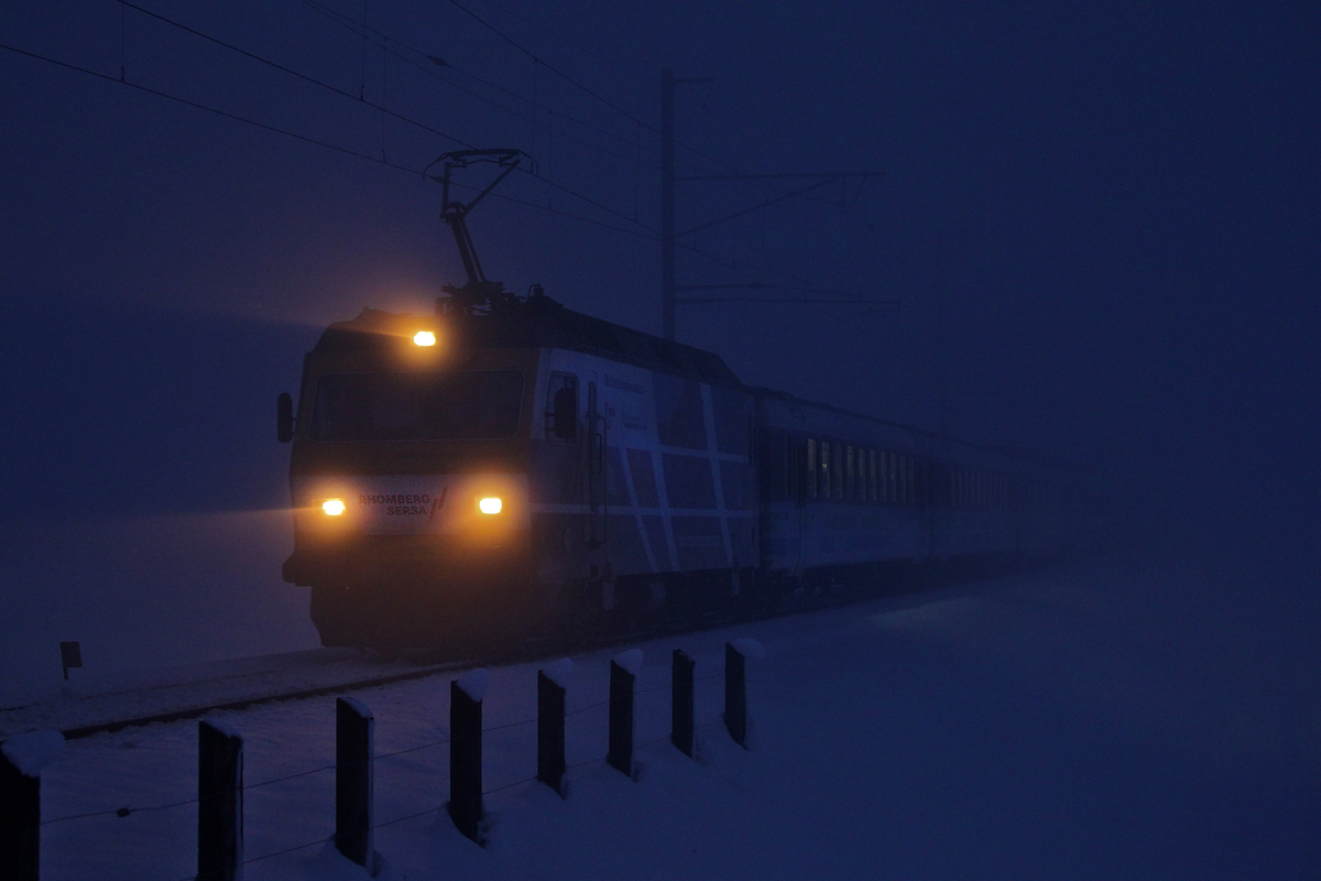 Die Zuglokomotive Re 456 093 der SOB braust frühmorgens zur blauen Stunde aus gefrierendem Nebel kommend mit dem Voralpenexpress Richtung Schmerikon.Bild Uznach vom 2.1.2015