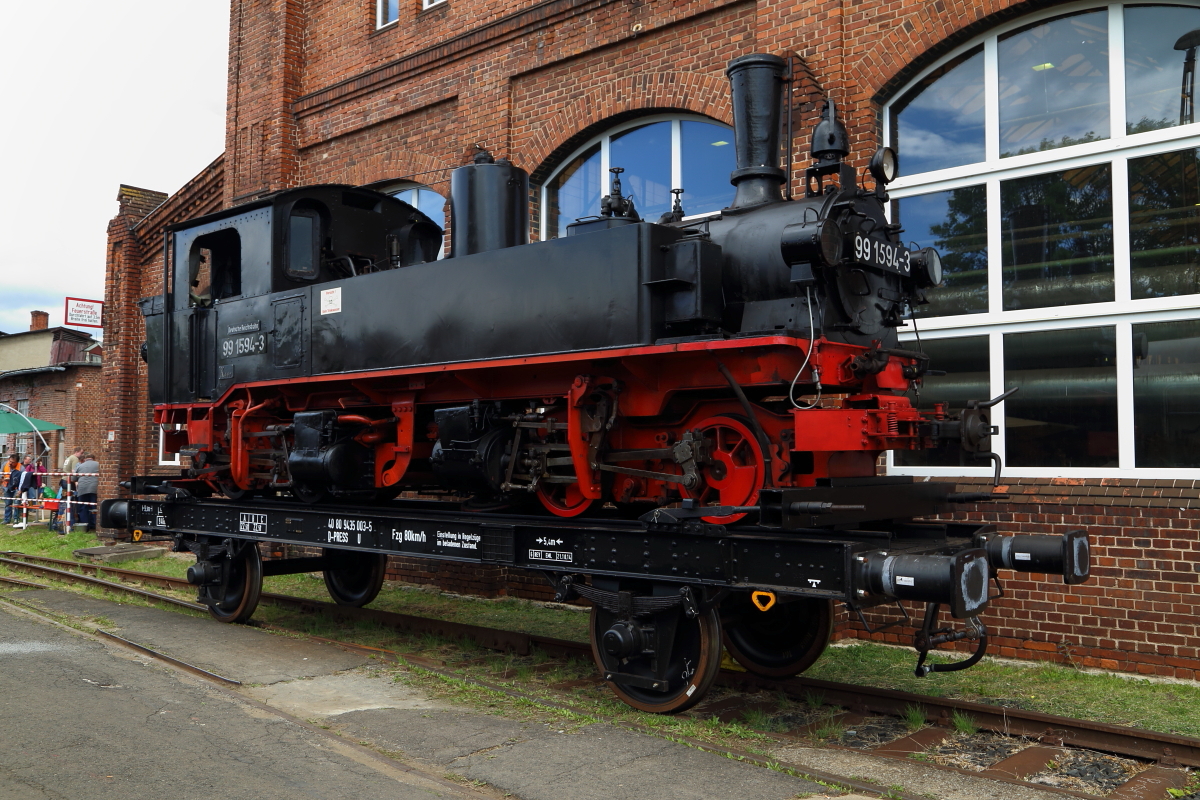 Die zurzeit nicht betriebsfähige 99 1594 der Preßnitztalbahn, ausgestellt auf einem Transportwagen, während der XXI. Dampfloktage am 05.09.2015 im DLW Meiningen.
Diese Maschine wurde 1914 bei der Sächsischen Maschinenfabrik Chemnitz (ehem. Richard Hartmann AG) gebaut und war bis 1976 auf der Strecke Wolkenstein-Jöhstadt im Einsatz. 1977 (nach Stillegung der Strecke) wurde sie an die norwegische Museums- und Touristikbahn Urskog Holandsbahnen  Tertitten  abgegeben, wo sie bis 1985 im Dienst stand. Ab 1988 war die Maschine wieder zurück in Deutschland und beim  Öchsle  beheimatet, wo sie 1990 auch kurzzeitig wieder unter Dampf stand. Ab 1995 befand sie sich dann als Ausstellungstück auf der Insel Rügen und kam 2006 zur betriebsfähigen Aufarbeitung ins rumänische Ausbesserungswerk  Remarul 16. Februarie , wo sie einige Testfahrten erfolgreich absolvierte. Die für Herbst 2006 geplante Indienststellung auf der Insel Rügen, kam aus diversen technischen und juristischen Gründen nicht zustande, sodaß sie wieder auf einem Abstellgleis in Putbus landete. Die Lok ist nun seit 2014 im Besitz der Preßnitztalbahn, wo man eine längerfristige betriebsfähige Aufarbeitung durchaus in Betracht zieht. (Quelle: Bimmelbahn.de) 