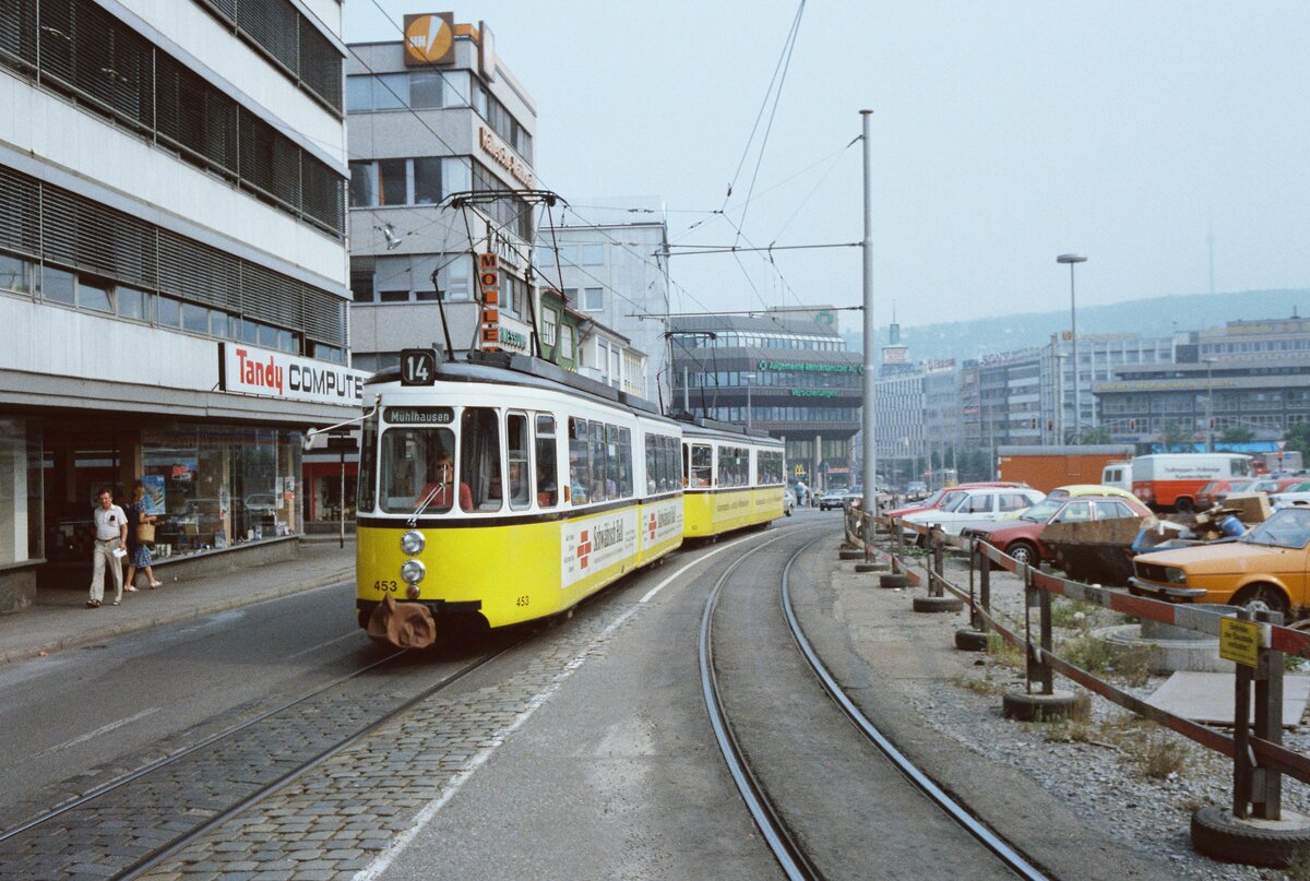 Diese Aufnahme der Stuttgarter Straßenbahn von 1983 datiert zurück in die Zeit des Stadtbahnbaus zwischen der Calwer Passage (in der Mitte) und der Straßenbahnstation Hohe Straße, welche der Straßenbahnzug der Linie 14 (mit zwei GT4) gleich erreicht.