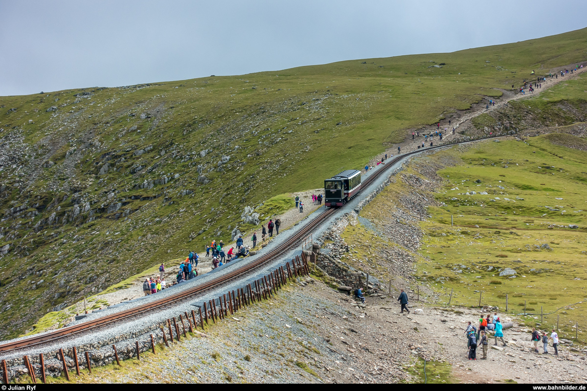 Diesellok 10 der Snowdon Mountain Railway erreicht am 15. August 2017 vom Gipfel her kommend die Kreuzungsstation Clogwyn. Trotzdem, dass der Snowdon an diesem Dienstag im Nebel liegt, ist der Wanderweg von Llanberis zum Gipfel sehr stark bevölkert.