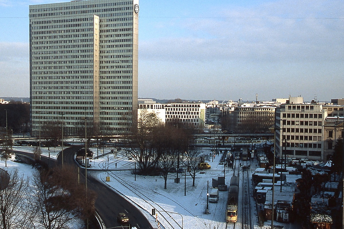 Dieser Blick auf den Düsseldorfer Jan-Wellem-Platz bot sich im Dezember 2009, im Vordergrund ein GT8 auf der Linie 712. Bis 1988 war hier der größte Straßenbahnknotenpunkt Düsseldorfs mit insgesamt acht Bahnsteigen. Mit der Inbetriebnahme der U-Bahn zum Hauptbahnhof verlor er viel von seiner Bedeutung. Von den vier in Ost-West-Richtung verlaufenden Gleisen sind zum Zeitpunkt der Aufnahme nur noch zwei vorhanden, die links sichtbaren beiden Bahnsteige für die Fernbahnlinien nach Krefeld und Duisburg wurden nur noch bei Umleitungen odere Betriebsstörungen benötigt. Inzwischen ist der Platz mit dem Kö-Bogen, einem Bau des Architekten Daniel Libeskind, überbaut, die Straße ist schon in einen Tunnel verlegt worden, die Straßenbahn wird nach Inbetriebnahme der Ost-West-U-Bahn im Februar 2016 ebenfalls Geschichte sein.