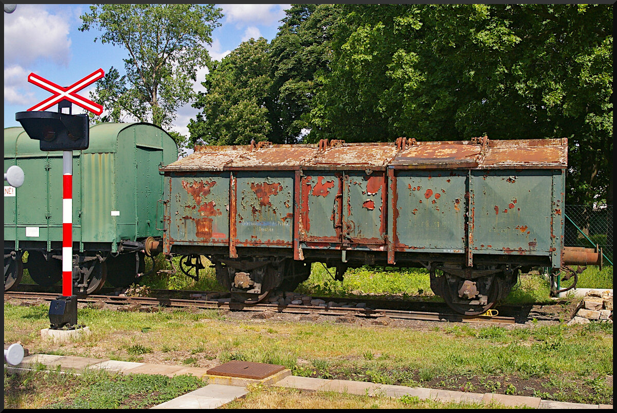 Dieser Klappdeckelwagen (Gattung U) ohne Nummer und leicht rostig stand am 21.05.2022 im Eisenbahnmuseum Jaroměř. Zu sehen ist auch ein altes Bahnübergangswarnsignal. Das querliegende Kreuz ist heute Gelb. Die beiden roten Warnlampen sind geblieben, es kam noch eine dritte weiße Lampe bei freiem Bahnübergang hinzu.
