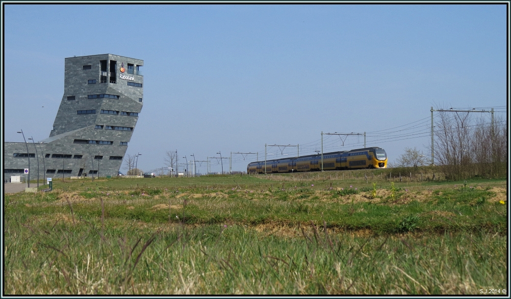 Dieses futuristische Gebäude steht unweit von Roermond in den Niederlanden und gehört der Rabobank.An gleicher Stelle ist gerade ein Virm Triebwagen der NS unterwegs. Aufnahme vom 29.03.2014.