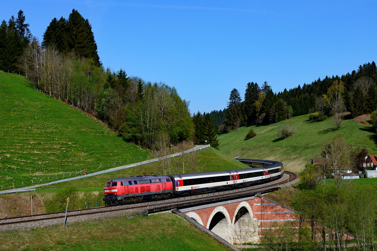 Dieses Jahr werden die EC Züge zwischen München und Zürich komplett über die KBS 970 geführt. Der Grund hierfür sind die Bauarbeiten auf der Strecke zwischen Buchloe und Leutkirch, die bereits der Vorbereitung der Elektrifizierung dienen. So kann man die Baureihe 218 noch in reizvoller Landschaft vor hochwertigen Reisezügen erleben. Am 22. April 2018 suchte ich die Gegend um Oberthalhofen auf. Am Viadukt, welches seit Eröffnung der Allgäubahn existiert, konnte ich den EC 191 auf seiner Fahrt nach München HBF aufnehmen. Obwohl der Zug nur mit einer Lok in Form von 218 465 bespannt war, verkehrte er ohne Verspätung. 
