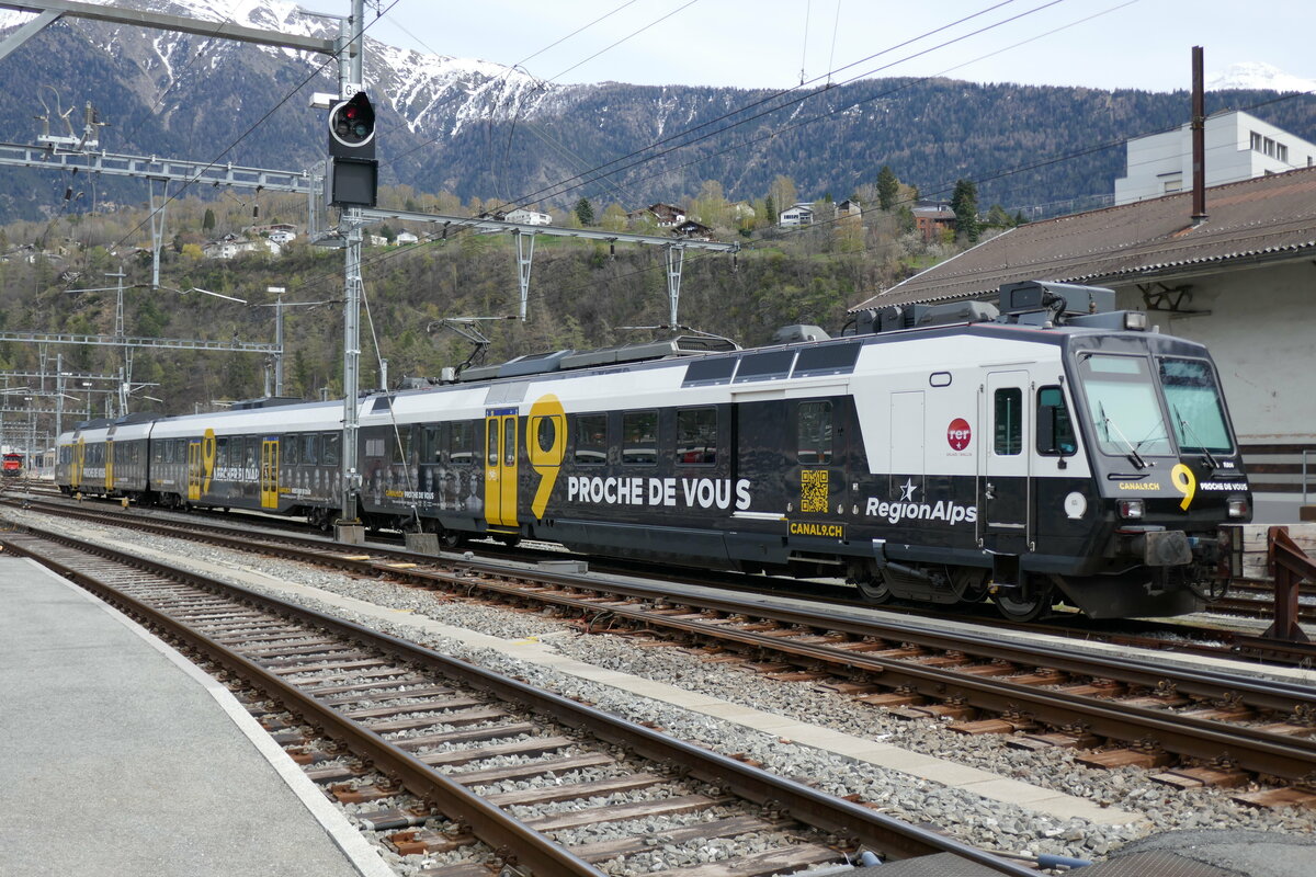 Domino RegionAlps RA14 mit der Kanal 9 Vollwerbung am 10.4.23 beim Bahnhof Brig abgestellt.