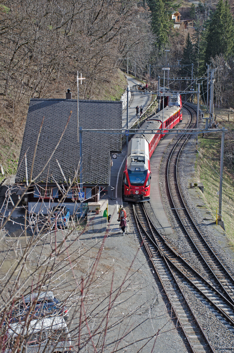 Donnerstag den 29.02.2024 (Schalttag/Schaltjahrtag) um 09:26 Uhr in der Gemeinde Arosa im Quartierteil Lüen (GR). Im Bahnhof Lüen-Castiel an der RhB Bahnlinie Chur – Arosa findet soeben eine Zugskreuzung statt. Von Arosa Talwärts fahrend und im Bahnhof auf Gleis 1 (am AG) haltend fährt der R16 mit der Zugnummer 1424 ein und hat Kreuzung mit dem Bergwärts fahrenden Gegenzug R16 1425 welcher auf Gleis 2 einfährt. Der Zug R16 1424 verkehrt von Arosa (ab um 08:49 Uhr) mit Halt auf Verlangen in Lüen-Castiel (an/ab 09:28 Uhr) nach Chur (an um 09:51 Uhr). Der Zug R16 1425 verkehrt von Chur (ab um 09:08 Uhr) mit Halt auf Verlangen in Lüen-Castiel (an/ab 09:28 Uhr) nach Arosa (an um 10:09 Uhr). Dies ist noch lange nicht die ganze Geschichte bei dieser Zugskreuzung. Am heutigen Tag und zufälligerweise genau bei diesen zwei Zügen werden noch Statisten an den Bahnhof getrieben. Es ist eine kleine Herde Ziegen welche vom Quartierteil Lüen (GR) auf der Strasse zum Bahnhof getrieben werden und dabei vom Kamerateam des TV-Sender  3sat“ aufgenommen werden. Der Grund für das Verfilmen ist das 110 jährige Jubiläum der Chur – Arosa – Bahn in diesem Jahr. Diese Informationen habe ich von einem Einheimischen welcher sich an den Aufnahmen beteiligt. Die Sendung wird im Herbst 2024 über den TV-Sender  3sat“ ausgestrahlt. Koordinaten GMS (Grad, Minuten, Sekunden): N 46° 49’ 53.6’’ O 9° 36’ 44.7’’