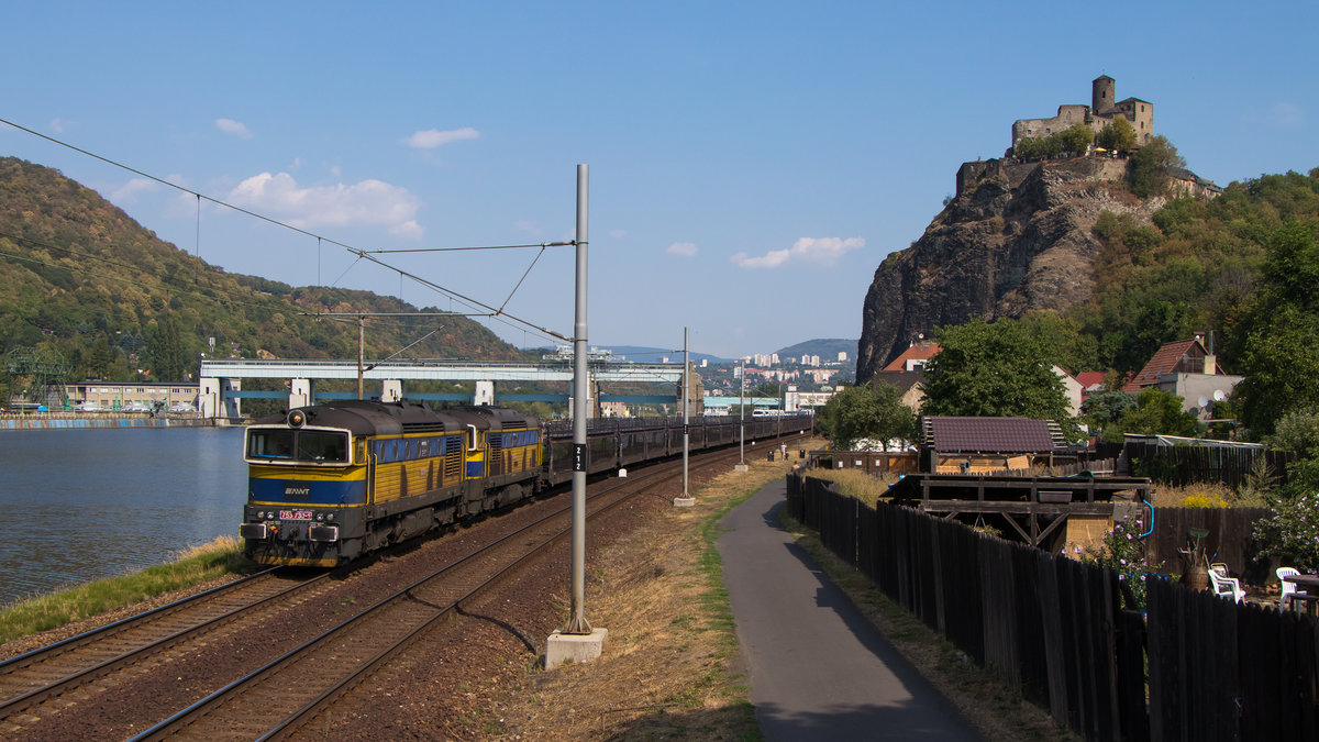 Doppelbrillenpower am 4. August 2018 in Usti nad Labem. 753 730-1 und 753 729-3 sind mit einem leeren Autozug unterwegs. Im Hintergrund sind die 2 markanten Bauten der Stadt zu sehn. 