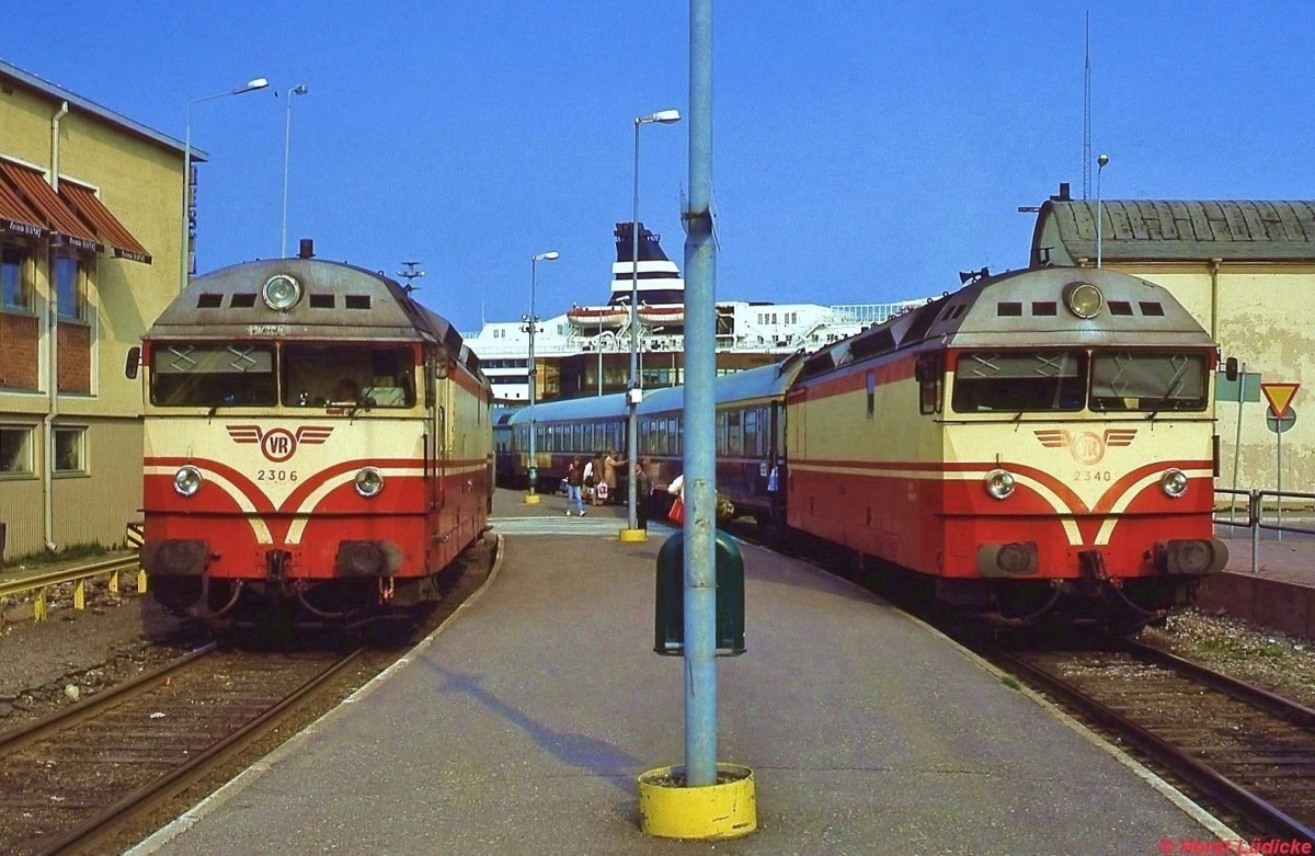 Dr13 3006 und 2340 warten im Mai 1988 im Hafenbahnhof Turku vor den Zgen nach Helsinki und Tampere auf die Fahrgste der Nachtfhren aus Stockholm. Die beiden ersten Dr 13 wurden 1962 bei Alsthom/Frankreich gebaut, die restlichen wurden zwischen 1963 und 1965 in Lizenz von Lokomo und Valmet in Finnland hergestellt. Die 2060 kW starken Maschinen mit einer Hchstgeschwindigkeit von 140 km/h trugen die Hauptlast des Verkehrs auf den nicht elektrifizierten Strecken und standen bis 2000 im Einsatz.