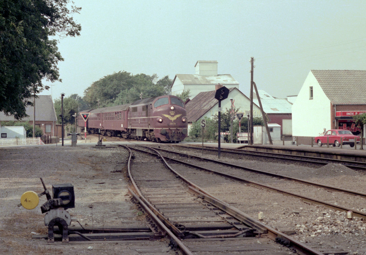 DSB: Das Bild zeigt die Nohab-Diesellok Mx 1029, die mit einem Personenzug den Bahnhof Hvidbjerg erreicht. Aufnahmedatum: 5. September 1976. - Scan eines Farbnegativs. Film: Kodak Kodacolor II. Kamera: Minolta SRT-101. 