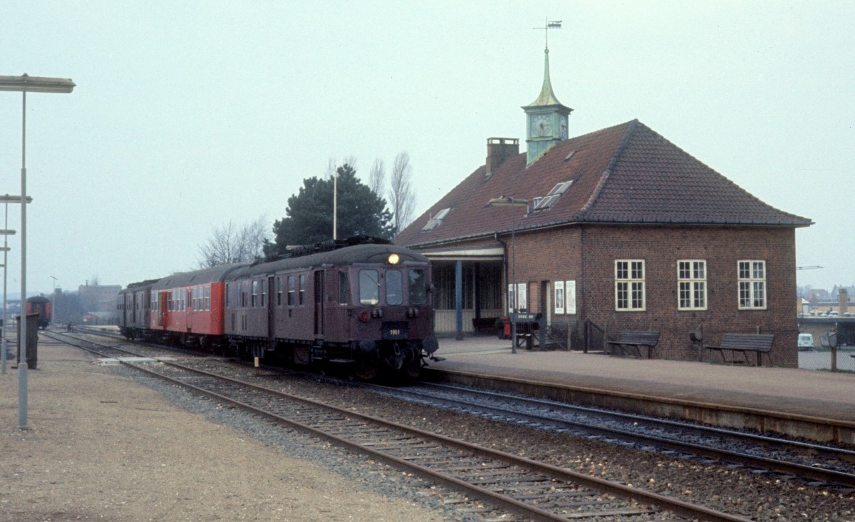 DSB-Kleinstadtbahnhöfe: Bahnhof Frederikssund. - Am 17. April 1976 steht ein Triebzug bestehend aus einem Triebwagen (Mo 1951), einem Nahverkehrspersonenwagen des Typs Bn als Mittelwagen und einem Triebwagen des Typs Mo. - Der Mo 1951 wurde 1935 von Scandia als Mo 211 mit einem B&W-Dieselmotor gebaut. 1941 bekam der Tw die Nummer 551; ab 1961 hiess er Mo 1951. Die Ausmusterung fand 1983 statt. - Am  27. Mai 1989 wurde die Verlängerung der Linie H der Kopenhagener S-Bahn nach Frederikssund eingeweiht. Gleichzeitig eröffnete die DSB einen neuen S-Bahnhof ein bisschen näher dem Stadtzentrum in Frederikssund und schloss den alten Bahnhof, der 1928 eröffnet worden war.
