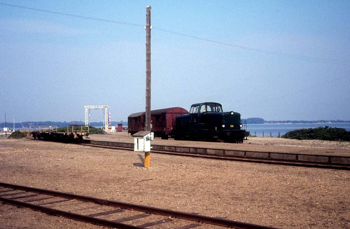 DSB: MT 159 steht am 5. September 1976 mit zwei Güterwagen in Glyngøre. - In den Jahren 1884-1979 gab es eine Bahnverbindung (DSB) zwischen Skive (auf der Bahnstrecke Langå - Struer) und Glyngøre (der Personenverkehr wurde jedoch im Jahre 1971 eingestellt). - Bis 1977 gab es eine Eisenbahnfährverbindung von Glyngøre (das Fährbett sieht man im Hintergrund) nach Nykøbing Mors auf der anderen Seite der Meerenge Salling Sund.