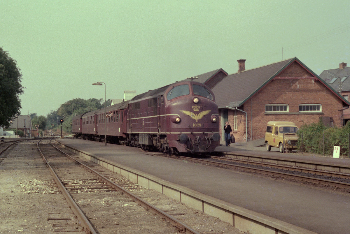 DSB: Mx 1029 hält am 5. september 1976 mit einem Personenzug im Bahnhof Hvidbjerg. - An vielen Bahnhöfen befand sich auch das örtliche Postamt; rechts sieht man ein Postauto des Typs Renault 4 - solche Autos benutzte viele Jahre das P&T, das dänische Post- und Fernmeldewesen, als Postautos. - Scan eines Farbnegativs. Film: Kodak Kodacolor II. Kamera: Minolta SRT-101.