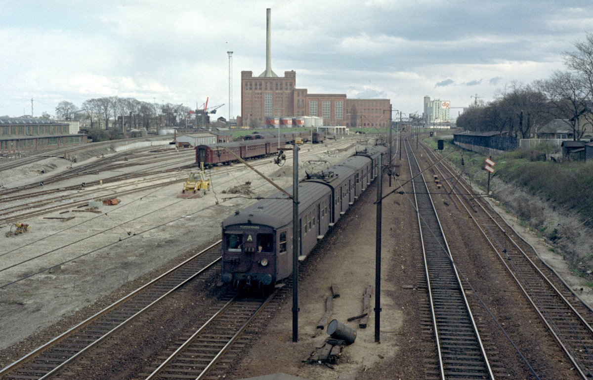 DSB S-Bahn Kopenhagen: Ein Zug der Linie A nähert sich am 29. April 1972 dem S-Bahnhof Svanemøllen. - Die Zuggarnitur besteht aus S-Bahnfahrzeugen der ersten Generation und zwar aus einem Steuerwagen (FS), einem Triebwagen (MM), einem Steuerwagen (FS) und einem Triebwagen (MM). - Links befindet sich die Bahnabstellanlage Helgoland. Im Hintergrund sieht man u.a. das Elektrizitätswerk Svanemøllen. - Scan eines Farbnegativs. Film: Kodak Kodacolor X. Kamera: Kodak Retina Automatic II. 