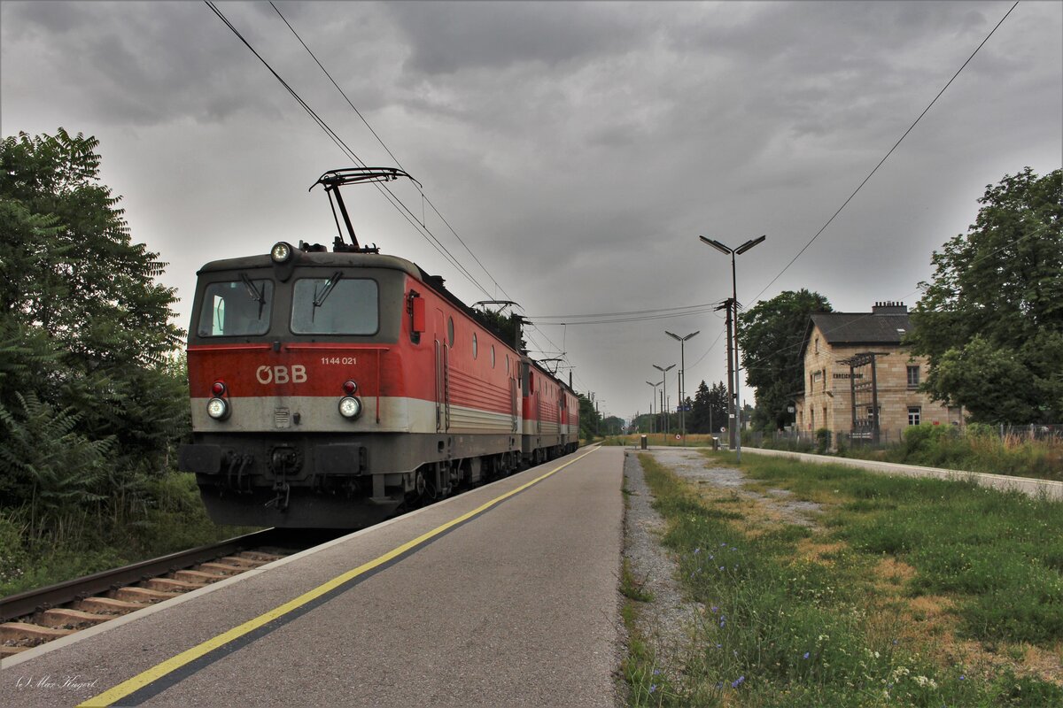 Dunkle Wolken ziehen über den Bahnhof Ebreichsdorf. Dieser wird im September dieses Jahres durch den neuen Bahnhof auf der neuen Pottendorfer Linie etwas außerhalb des Ortes ersetzt.
Die 1144 021, 1144 056 und 1144 238 warten als DG54072 von Graz Vbf nach Wien Zvb hier auf die Weiterfahrt.