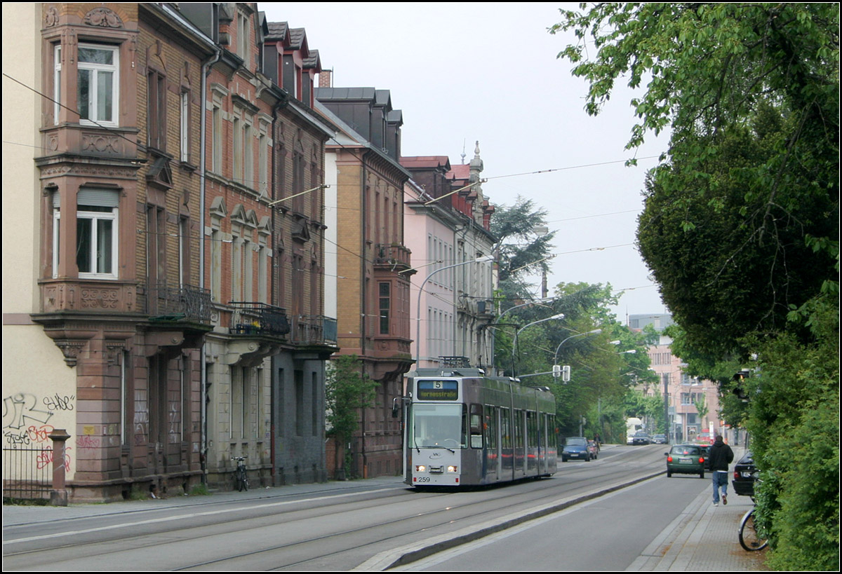 Durch Freiburg-Wiehre ins Rieselfeld -

Blick in die Basler Straße die mit dem Bau der Straßenbahn zur Fahrradstraße wurde. Der Bahnkörper, der auch von Einsatzfahrzeugen befahren werden kann zeigte keine trennende Wirkung im Straßenbild. Optimal ist es wenn auf Masten verzichtet und die Fahrleitung an den Häusern aufgehängt werden kann. Die Blickrichtung ist gen Westen.
 
11.05.2006 (M)

