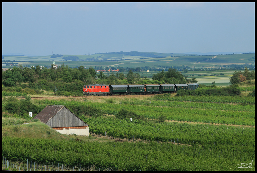 Durch die Weinberge um Retz fährt die blutorange Diesellok 2143 070 mit dem Reblaus Express 16974 von Retz nach Drosendorf.
3.6.2018