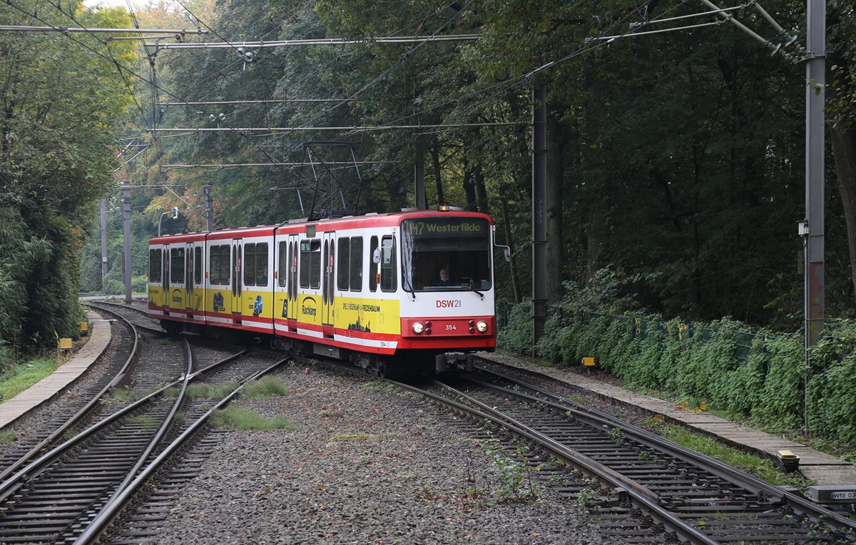 Durch eine wunderschöne Herbstlandschaft verkehrt derzeit die U-Bahn Linie 47 in den Außenbereichen von Dortmund. Zur echten U-Bahn wird sie nur im Stadtkern Bereich. Eine Besonderheit dieser Linie: Zwischen Obernette und der Stadtmitte überquert diese Strecke in gleicher Höhe im neunzig Grad Winkel eine zweigleisige elektrifizierte Eisenbahnstrecke! Eine echte Eisenbahnkreuzung! 
Das Foto zeigt den Triebzug 354 der DSW 21 auf der Linie U 47 am 18.10.2020 bei der Einfahrt in den Endbahnhof Westerfilde. 