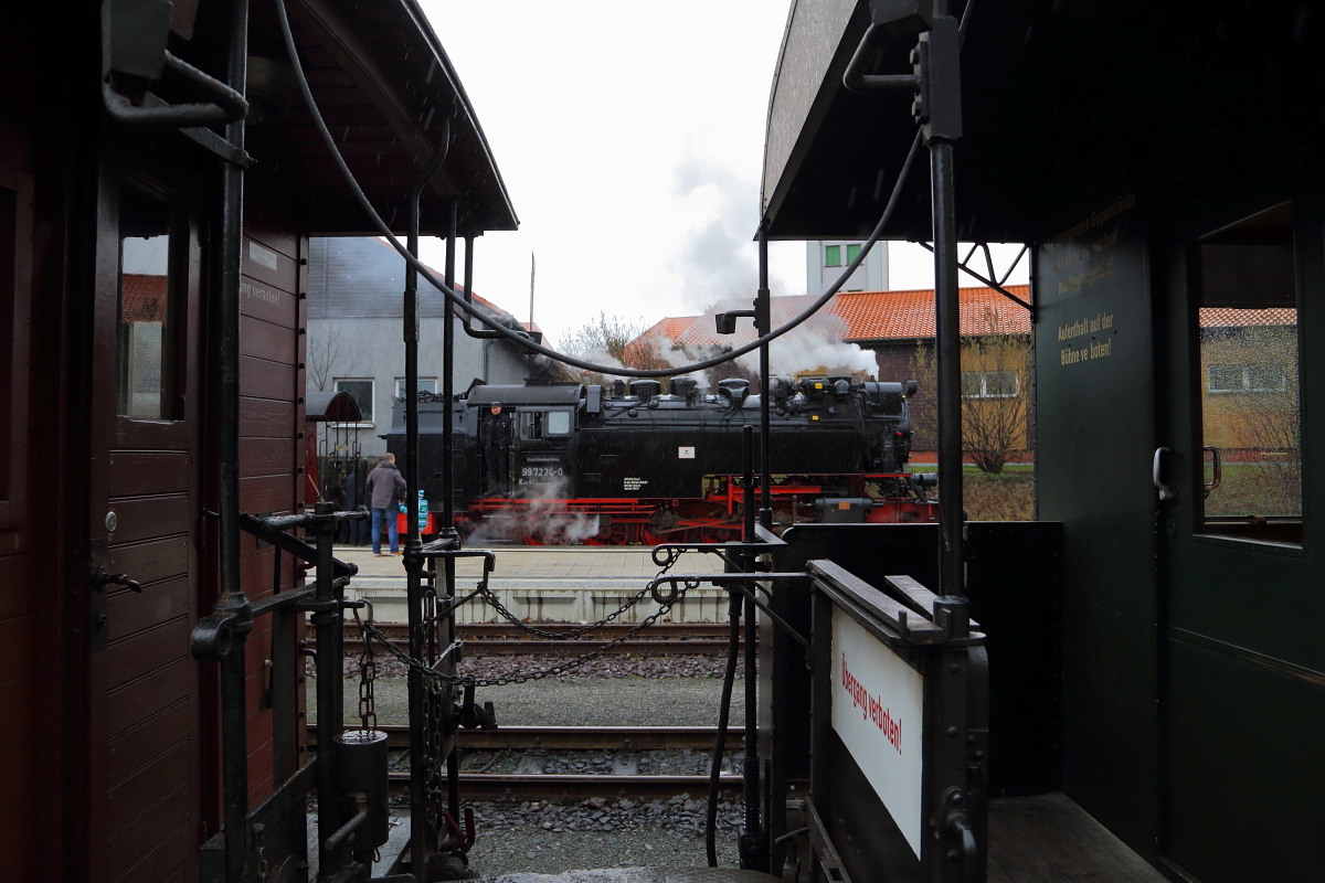 Durchblick bei Regen. Zwischen zwei historischen Waggons eines Sonderzuges wird der Blick frei auf 99 7234, welche in Kürze mit P8903 nach Eisfelder Talmühle aufbrechen wird. Die Aufnahme entstand am 05.02.2016 im Bahnhof Wernigerode.