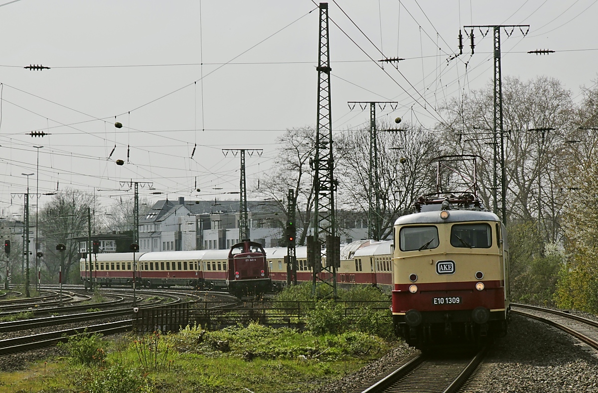 E 10 1309 legt sich am 06.04.2019 mit dem AKE-TEE bei Köln West in die Kurve, in der Bildmitte ist 211 345-4 zu erkennen, die in der Gegenrichtung nach Köln Süd unterwegs ist. Tele-Aufnahme vom Bahnsteigende.