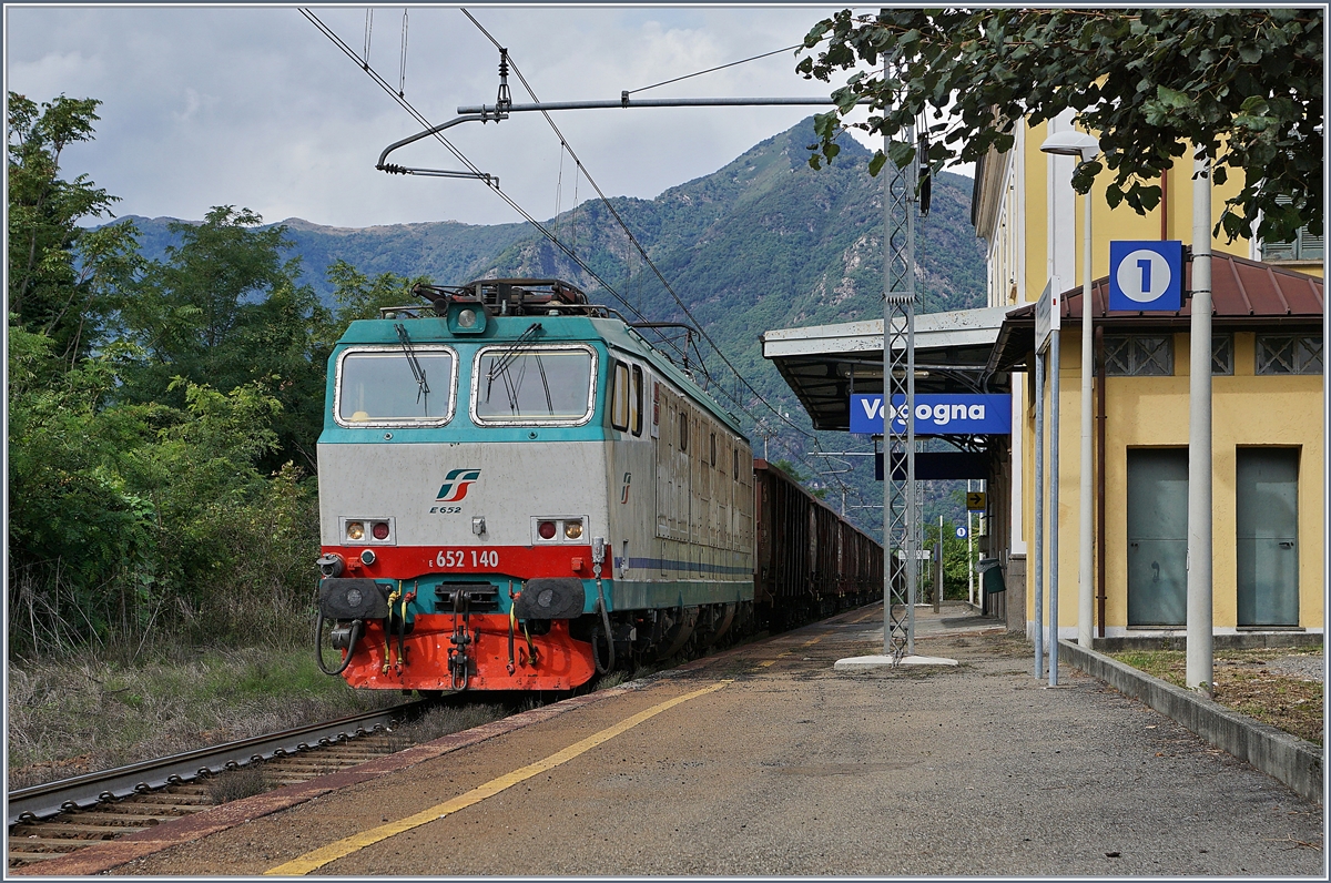 E 652 140 fährt mit einem Güterzug aus Eaos (oder ähnlichen Wagen) durch den Bahnhof von Vogogno. 
Der Bahnhof verfügt über dieses Gleis der Stecke Domodossola - Novara und etwas zwanzig Meter weiter Westlich über Gleise der Doppelspur Domodossola - Milano. 
Die beiden Strecken sind erst in Premosello verknüpft und verlaufen etliche Kilometer mehr oder weniger Parallel.  
18. Sept. 2017