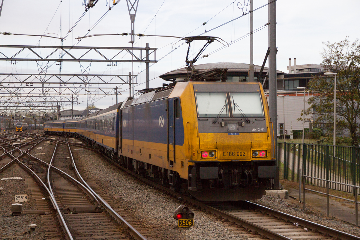 E186 002 verlässt Amsterdam Centraal am Zugschluss von einem Intercity Direct nach Brussel-Zuid/Midi. Eine Traxx Sandwich-Traktion ist hier wegen des ETCS-Zugsicherungssystems auf der HSL Schiphol-Rotterdam notwendig, am 08.11.2022.