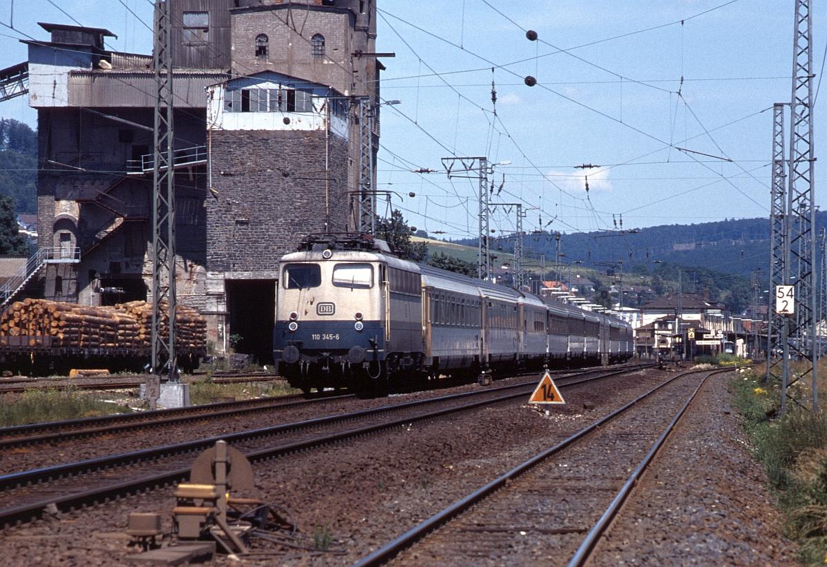 Ebenfalls ein markanter Punkt an der Kinzigtalbahn war die bis 1984 betriebene und 2003 abgerissene Misch- und Verladeanlage für Basalt südlich des Bahnhofs Wächtersbach. 110 345 passiert am 22.9.1993 mit einem IC aus Leipzig das Bauwerk. Auch das Gleis der Kleinbahn nach Bad Orb (rechts) ist noch in Betrieb.