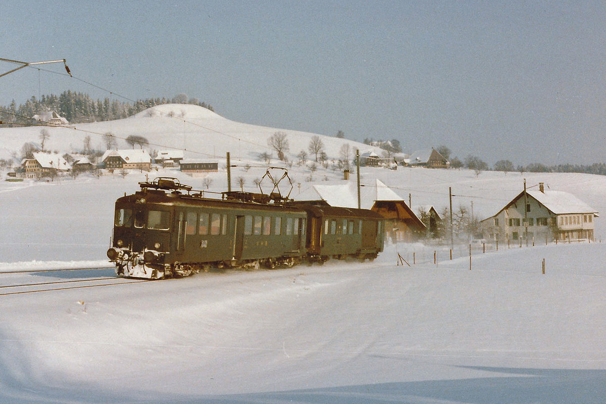 EBT/VHB: Als auf der ehemaligen VHB noch planmässige Züge verkehrten.
Regionalzug bestehend aus einem BDe 4/4 I und einem Postwagen zwischen Huttwil und Sumiswald unterwegs im Januar 1985.
Foto: Walter Ruetsch 
