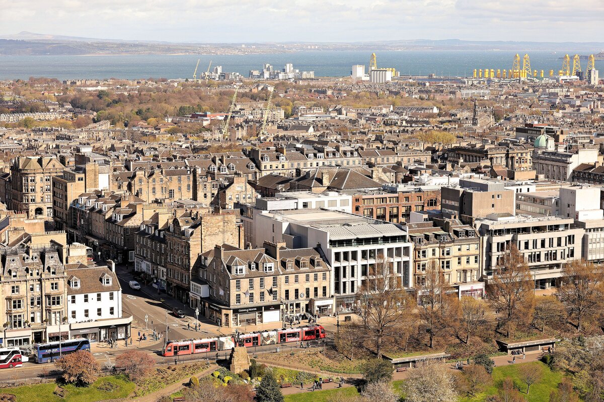 Edinburgh Tram in der Princes Street in der Edinburgh Neustadt (diese wurde ca. 1767 bis 1850 gebaut). Hinten sind die Hafenanlagen zu sehen, wohin das Tram f�hrt. 12.April 2026 
