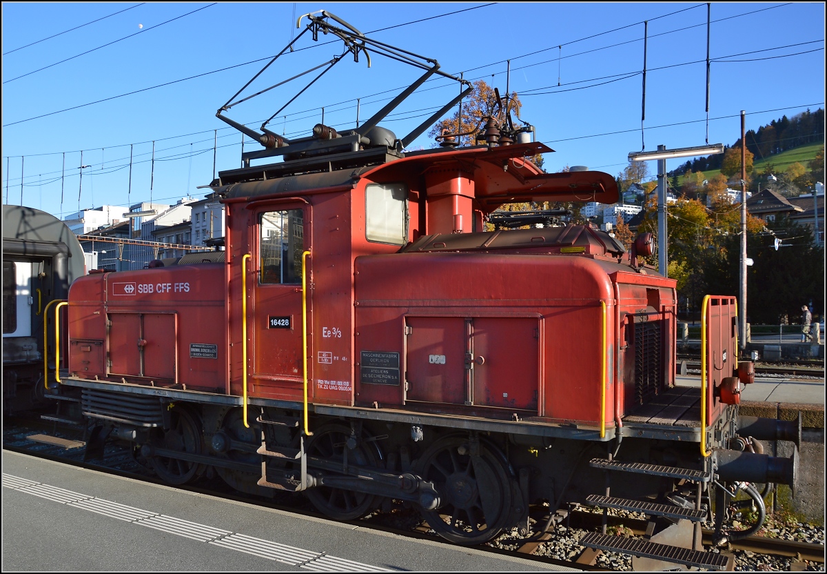 Ee 3/3 16428 in St. Gallen. November 2014. 

Diese kleinen Rangierloks könnte man auch als halbe Krokodile bezeichnen, denn den grundlegenden Aufbau und Winterthurer Schrägstangenantrieb bekamen sie von der Köfferlilok Ce 6/8 I, dem  Krokodilsprototypen . So basiert sie auf einer Konstruktion aus dem Jahre 1919, diese Konstruktion wurde auch bei der Ce 6/8 III verwendet. Dennoch wurde die Lok von Sie wurden von 1923-1966 nur mit kosmetischen Änderungen in sieben Serien gebaut. Hinzu kamen noch Zwei- und Viersystemloks. Die Serie litt nicht mehr an Übergewicht, so konnte das Laufrad entfallen. Sie wurden überall in der Schweiz auf den Bahnhöfen als Rangierloks eingesetzt. Das St.Galler im Bild Exemplar entspringt der 5. Serie die zwischen 1951 und 1956 gebaut wurde.