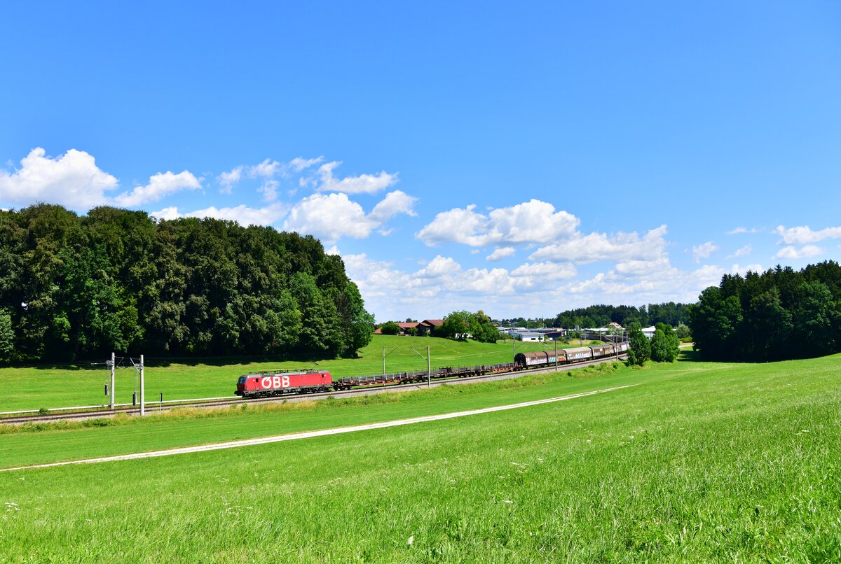 Ein von 1293 084 traktionierter Güterzug wird am 04.07.2026 in den Feldern von Axdorf westwärts befördert.