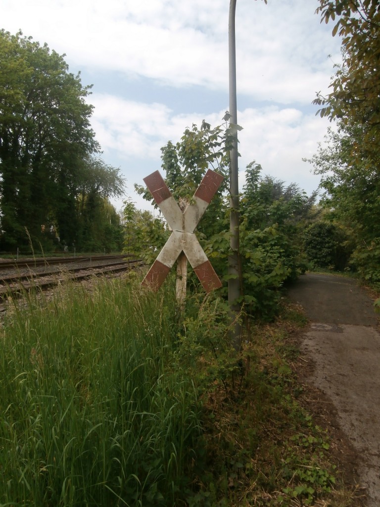 Ein altes Andreaskreuz weist noch heute auf den mittlerweile stillgelegten Bahnübergang hin. Die Strecke links ist die KBS 487 (Eiserner Rhein).      Reindahlen 26.04.2014