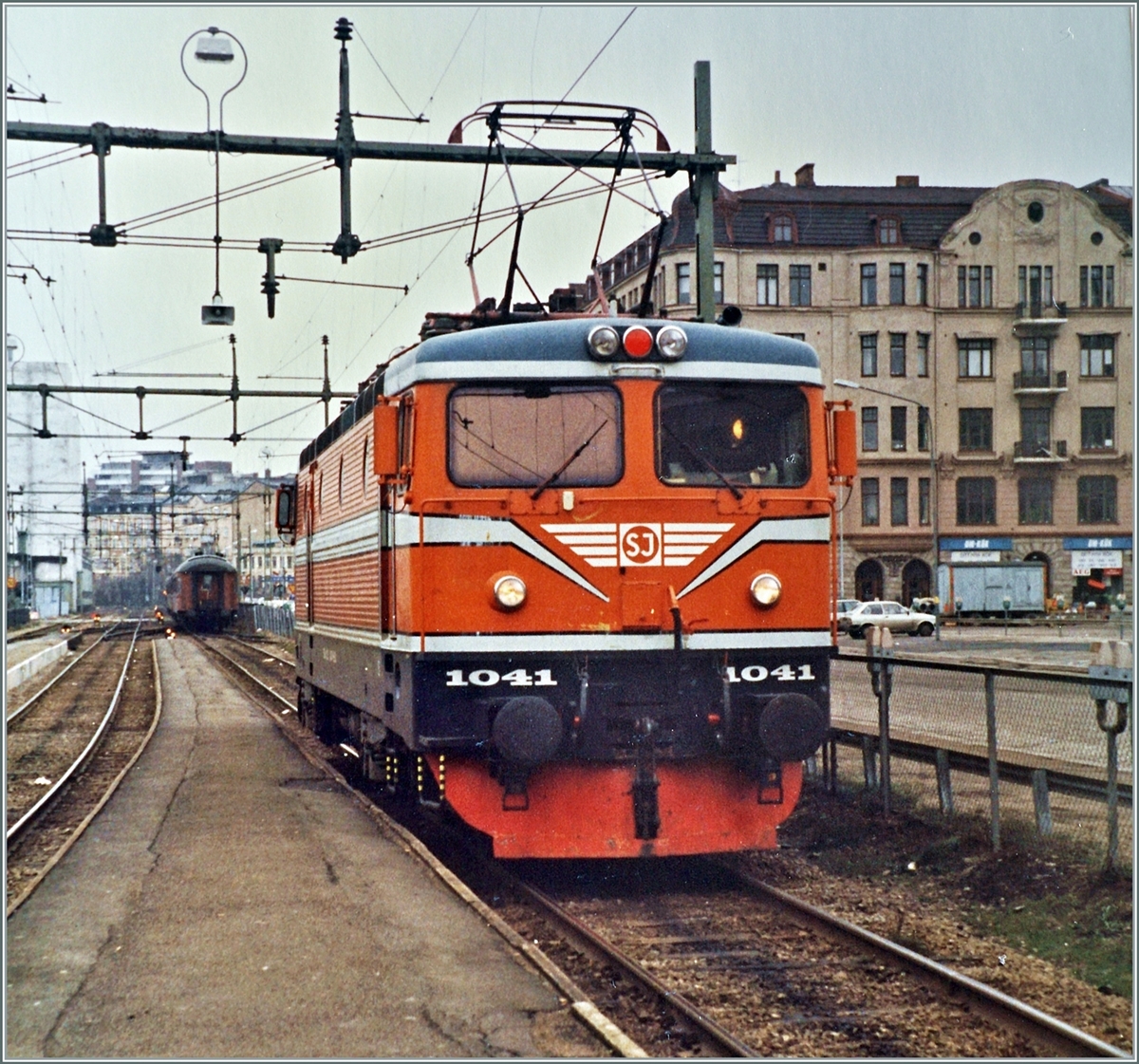 Ein altes Bild aus dem Fährhafen Bahnhof von Helsingborg. Die SJ Rc2 1041 ist dort nach der Ankunft ihres Zuges, der weit im Hintergrund wegezogen wird auf Rangierfahrt. 

Noch bis ins Jahr 2000 wurden hier Züge trajektiert, dann nahm die direkte Tunnel-Brücken Strecke von København nach Malmö den Betrieb auf. 
Das Analogbild wurde fotografiert und dann bearbeitet, was zu einem besseren Resultat führte als alle andern Versuche.

Analogbild vom 14. Feb. 1988