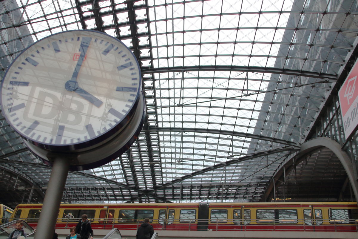 Ein Bahnhof aus Glas. In der Uhr spiegelt sich das Logo der Deutschen Bahn, welches über dem Eingang des Bahnhofs platziert ist.

Berlin Hauptbahnhof, 17. Oktober 2016