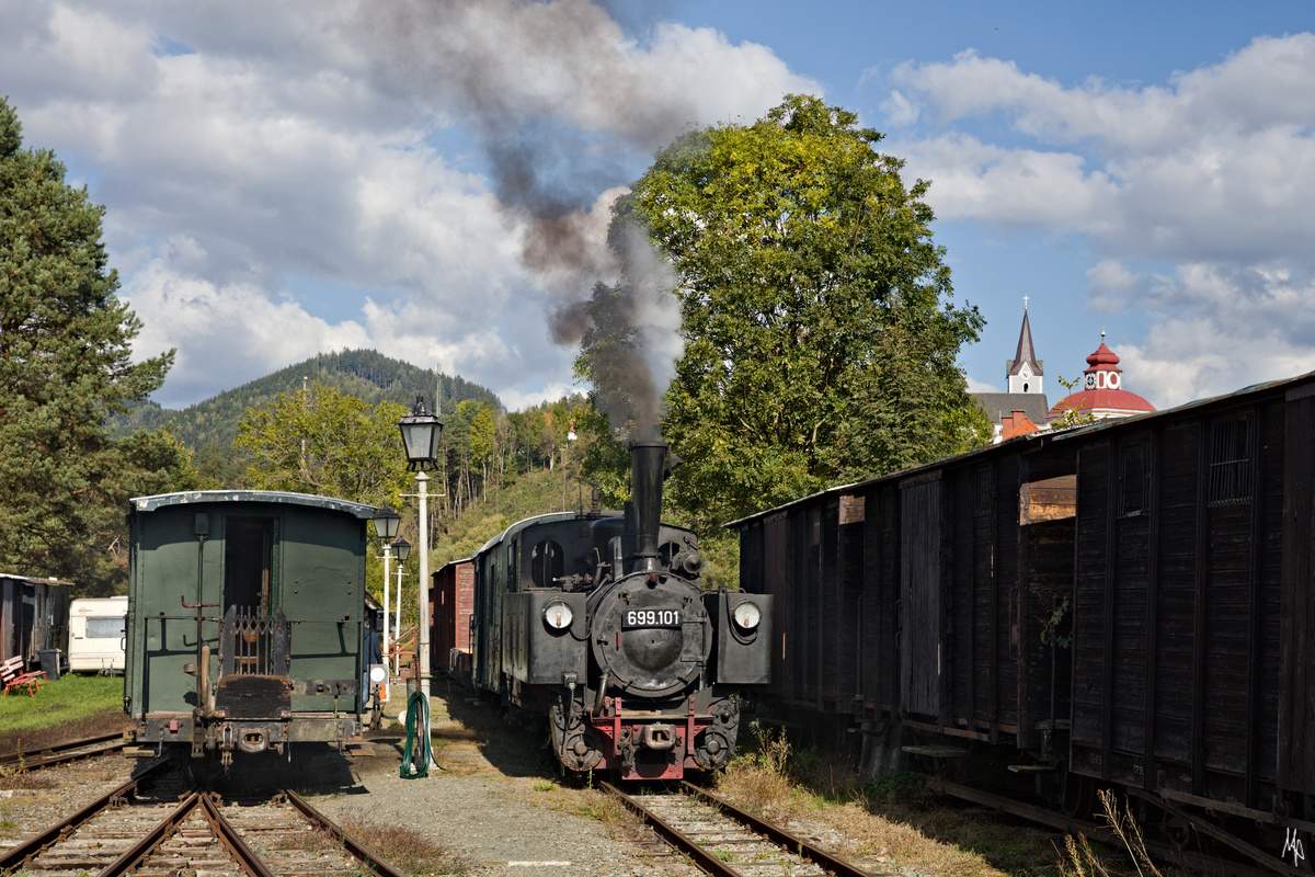 Ein Bahnhofsbild von Treibach-Althofen, wo die 699.101 der Gurktalbahn vor einem Güterzug auf die Abfahrt wartet. (09.10.2021)