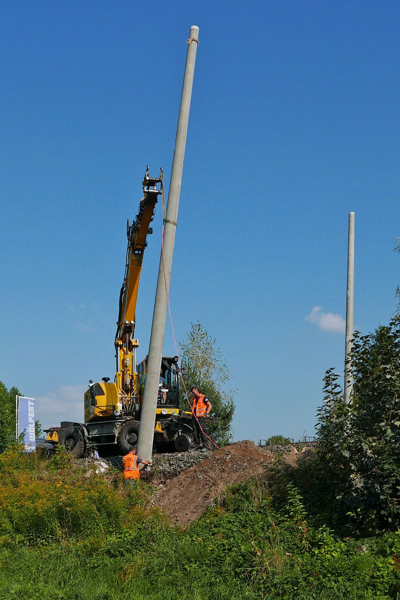Ein Bauarbeiter und der Maschinenfhrer eines Zweiwegebaggers A 922 Rail werden bentigt, um Oberleitungsmasten aus Beton aufzustellen. Meckenbeuren, 21.09.2020