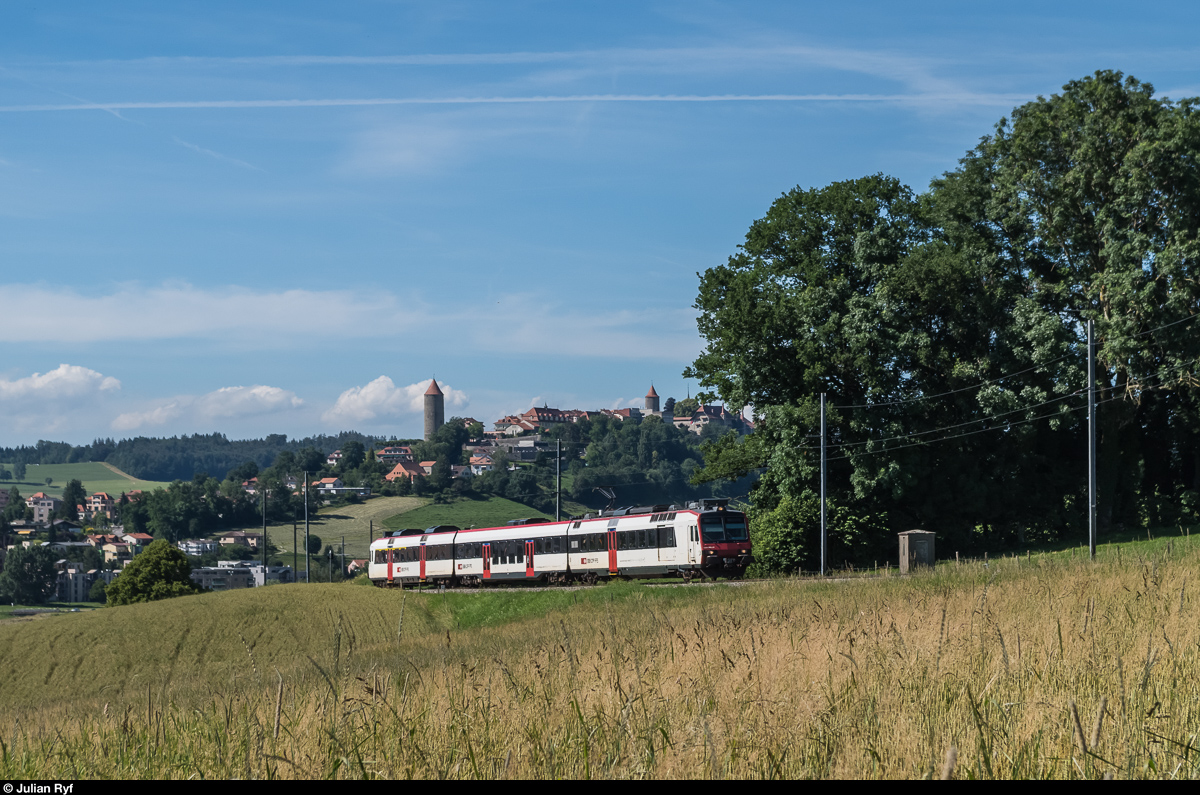 Ein DOMINO-Pendelzug fährt am 7. Juli 2016 bei Mézières als RE in Richtung Bulle. Im Hintergrund das Städtchen Romont.