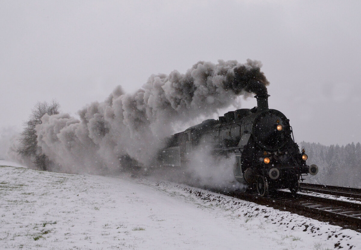 Ein Elefant kehrt heim – Überführung von C 5/6 2978 (SBB Historic) in die Schweiz - Tag 2: Bei Schneetreiben und mit Volldampf kommt die bayerische S 3/6 3673 mit ihrem Sonderzug die Steigung von Heimenkirch im Allgäu nach Oberhäuser hinauf geeilt. Stunden zuvor hatte sie die C 5/6 2978  Elefant  mit Unterstützung der V100 1365 von Nördlingen nach Friedrichshafen gebracht. 02.04.2022 