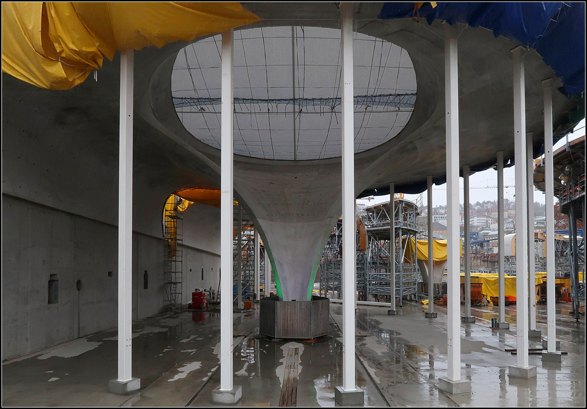 Ein erster Eindruck der zukünftigen Bahnsteighalle -

Auffälliges architektonischer Merkmal des neuen Stuttgart Hauptbahnhofes sind die Kelchstützen mit den sogenannten Lichtaugen. Eine davon wurde schon betoniert und von ihrer Verschalung befreit und ermöglicht einen ersten Eindruck der gerundeten Formen aus Sichtbeton der neuen Stuttgarter Bahnsteighalle. Der Bahnhof wird einen gewissen Höhlencharakter erhalten. Planer sind Ingenhoven Architects aus Düsseldorf.

Solange die Deckenteile noch nicht zusammengewachsen sind müssen diese weiße Stahlstützen die Auskragungen stützen.

Tage der offenen Baustelle, 05.01.2019 (M)