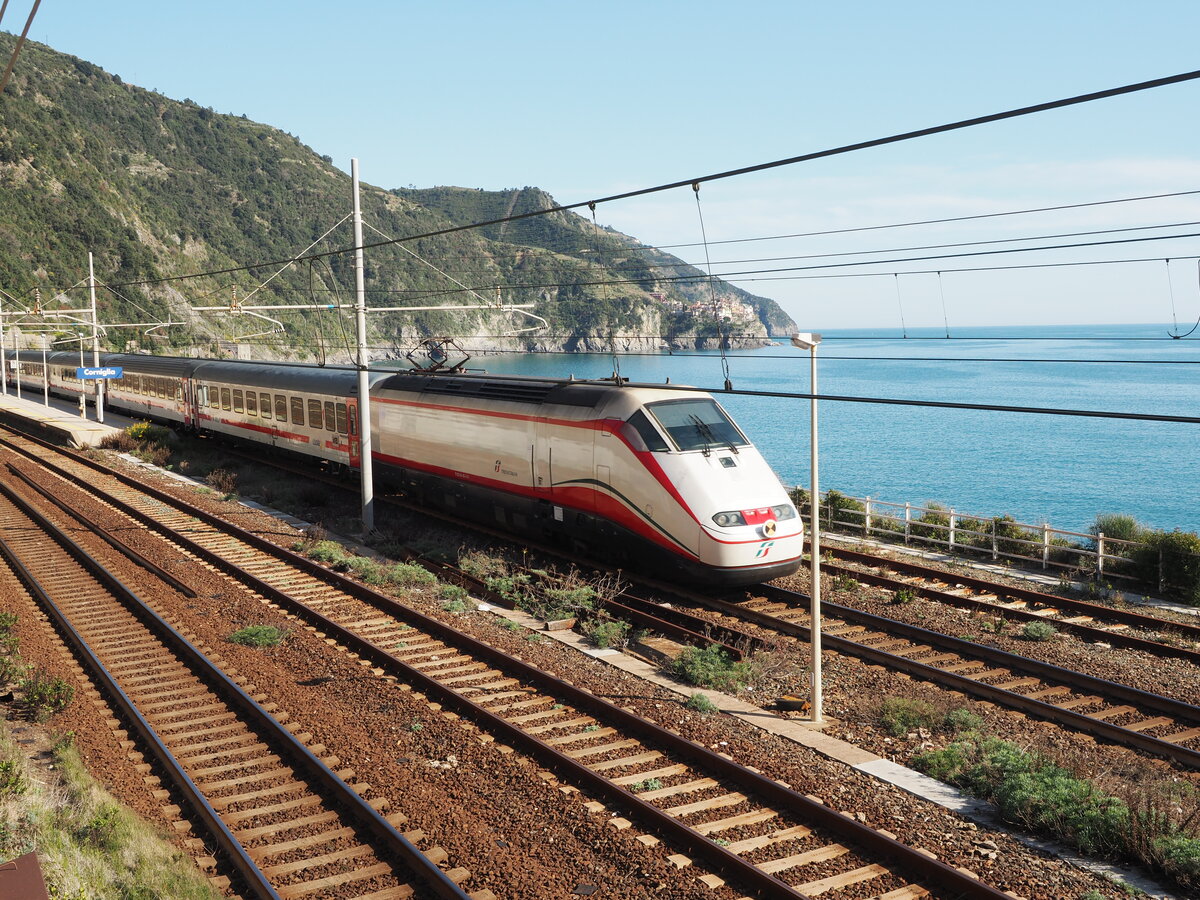 Ein  Frecciabianca  ist auf dem Weg durch den Bahnhof Corniglia (Cinque Terre).
Im Hintergrund das bekannte Dorf Manarola.

Aufgenommen von der Straße, etwas oberhalb des Bhf.

Corniglia, am 15.04.2022