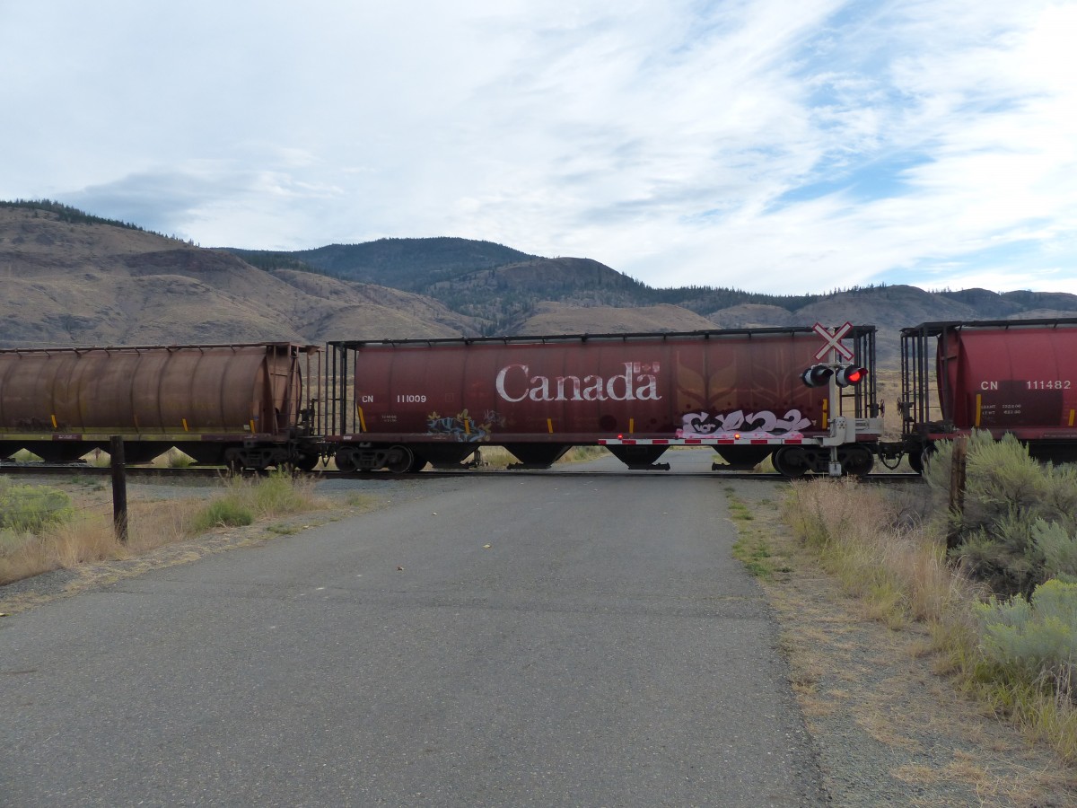 Ein Getreidetransportwagen der CN am 02.09.2013 an einem Bahnhbergang bei Juniper Beach Provincial Park.