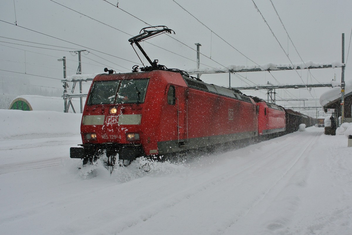 Ein Gterzug der DB pflgt sich durch den Neuschnee in Airolo auf Gleis 1. An der Spitze des Zuges sind die 185 129-4 und die 185 112-0, hinten schiebt die 185 099-9, 07.02.2014.