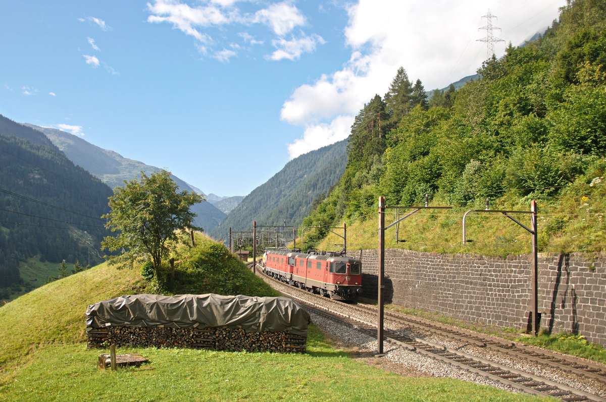 Ein Güterzug, geführt von der Re 4/4 II 11337 und einer unbekannt gebliebenen Re 6/6, fährt gemächlich bei angenehmen Morgen-Temperaturen bei Wassen in Richtung Norden. Aufgenommen am 29.07.2016