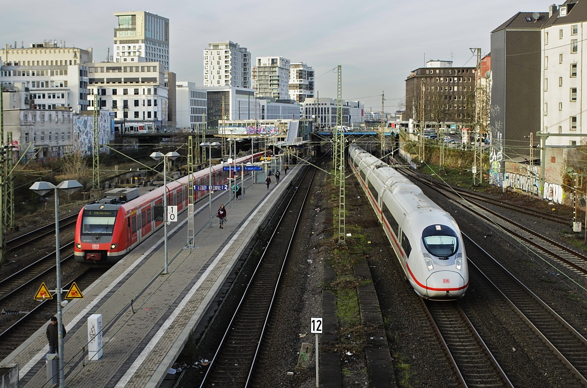 Ein ICE Velaro fährt am 18.12.2018 kurz vor dem Düsseldorfer Hauptbahnhof am S-Bahn-Haltepunkt Wehrhahn vorbei, an dem gerade 422 027-3 als S 6 nach Köln-Worringen auf die Weiterfahrt wartet