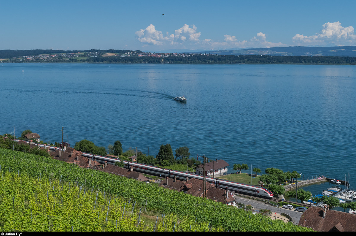 Ein ICN durchfährt am 18. Juli 2016 ohne Halt Ligerz am Bielersee, während das Motorschiff Berna gerade die Ländte des Ortes ansteuert. 