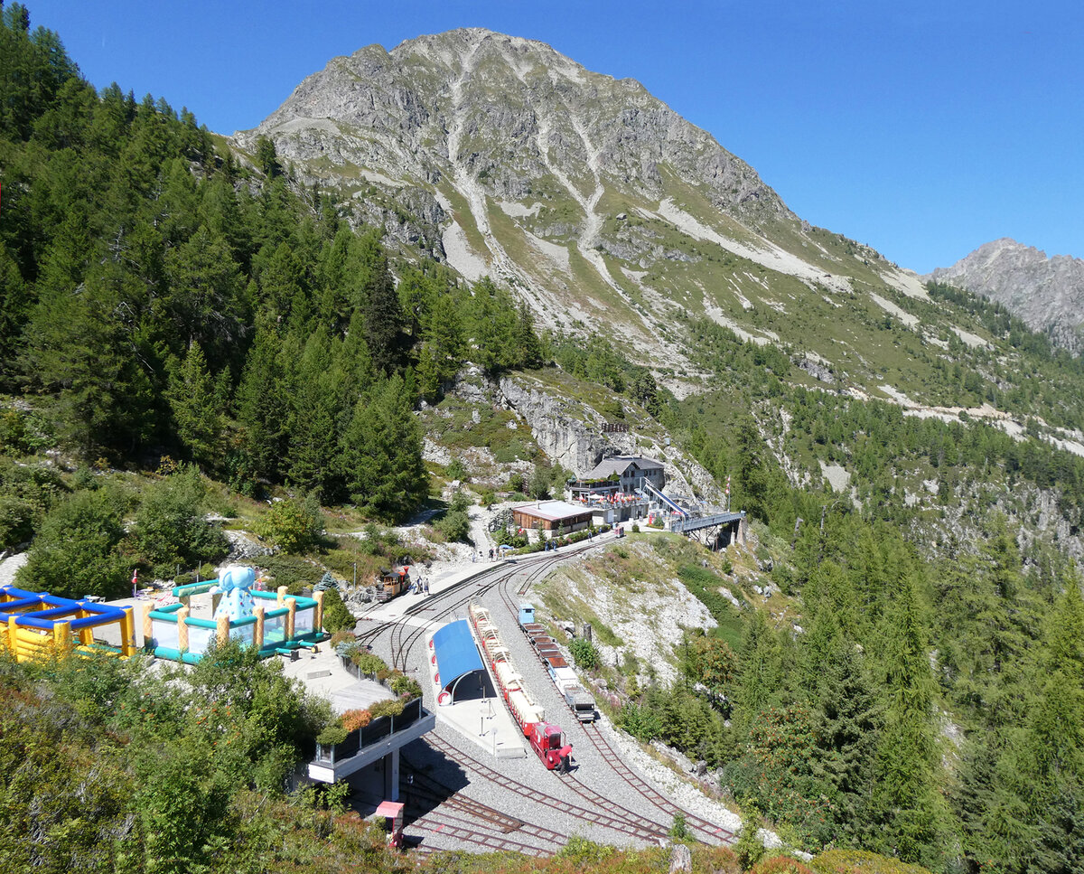Ein Juwel in der Walliser Berglandschaft: Bahnhof Les Montuires (1821 müM) mit dem roten Panoramic Train, der die Touristen auf einer imposanten Strecke am Berghang in Richtung Stausee Lac d'Emosson bringt. Lac d'Emosson, 25.8.2025