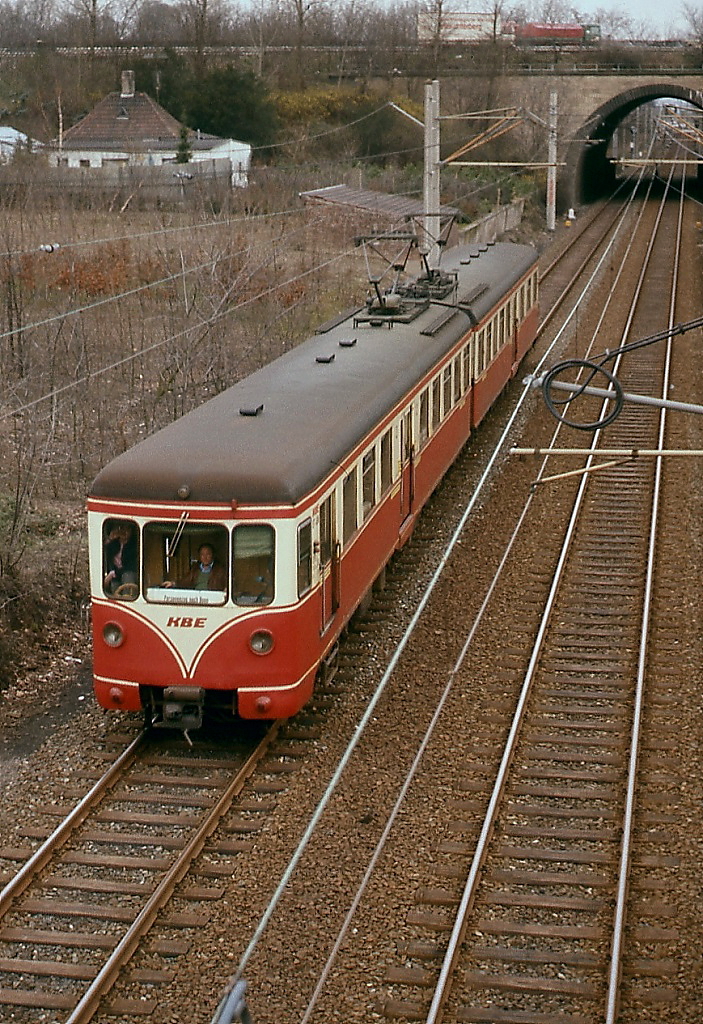 Ein KBE-Triebwagen fährt im März 1978 bei Rodenkirchen als Personenzug in Richtung Bonn. Dem Triebwagenführer scheint der Fotograf auf der Straßenbrücke nicht ganz geheuer zu sein.