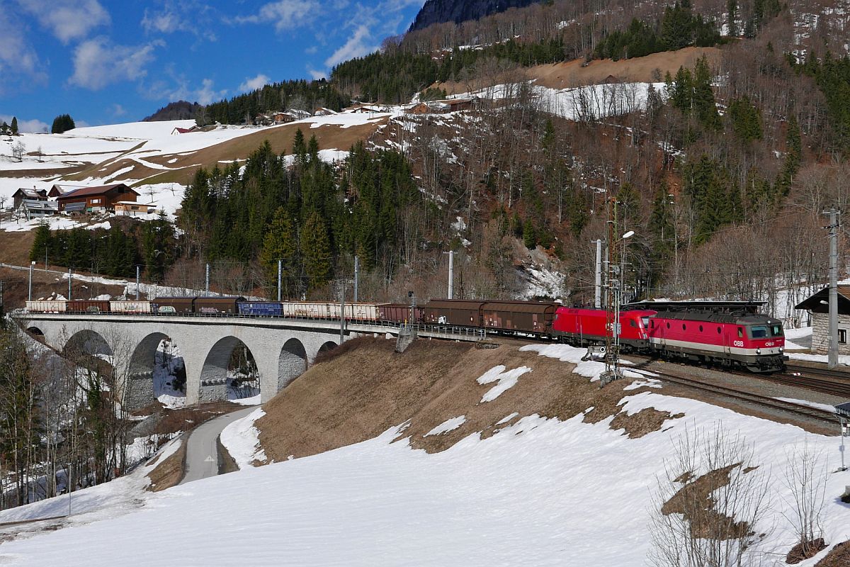Ein Lok der Baureihe 1144 und 1016/1116 überqueren mit dem aus 11 Wagen gebildeten Güterzug den Hölltobel in Dalaas (05.03.2019).
